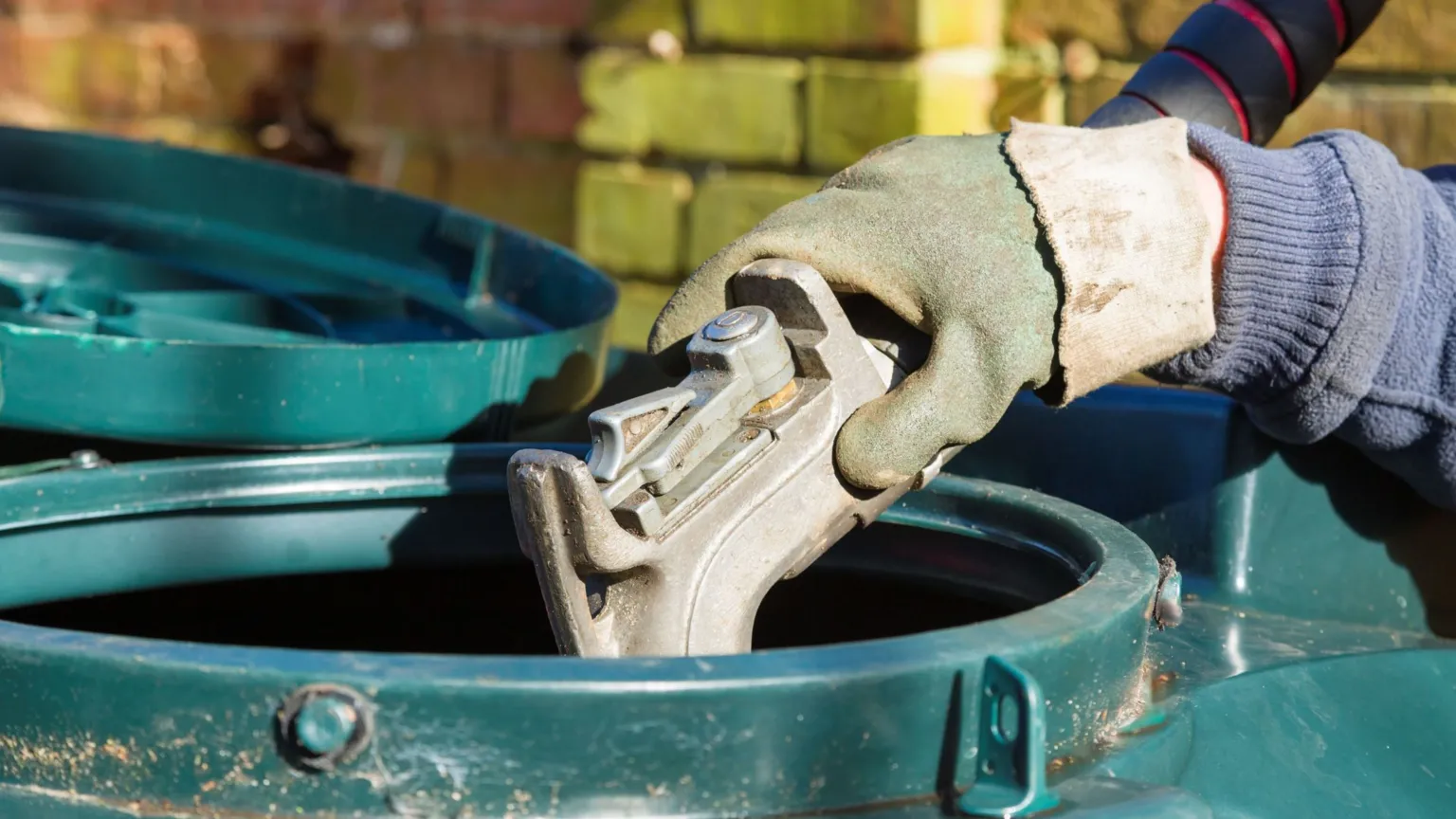 Getty Images A person's gloved hand holds the end of fuel pipe nozzle as they fill a large, green plastic tank with heating oil.