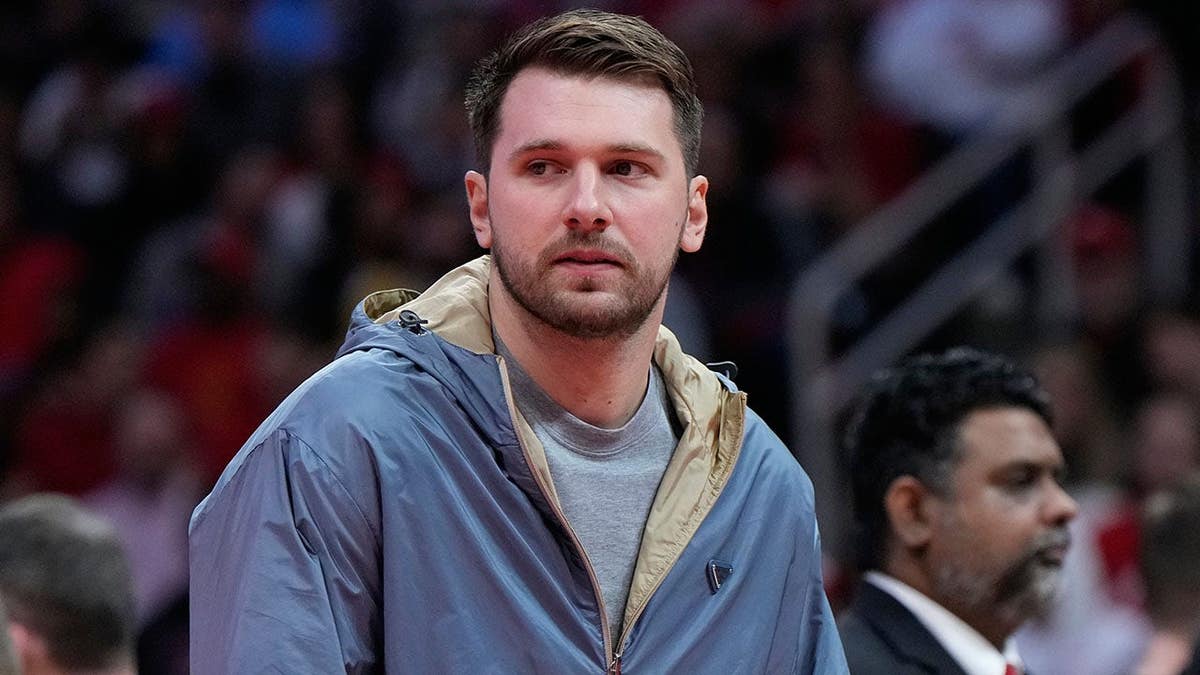 Luka Doncic holding a basketball during a timeout in an NBA playoff game.