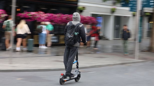 a person rides an e-scooter on a city street