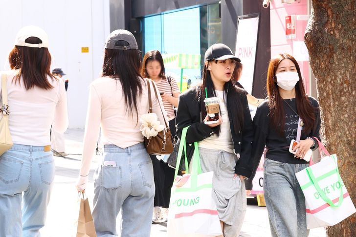 Foreign tourists walk with shopping bags along a street in Myeong-dong in Seoul, Monday. Yonhap