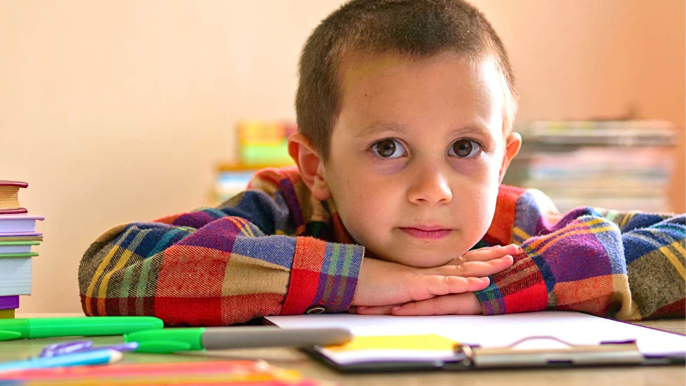 grade-school age boy looking thoughtful at a table